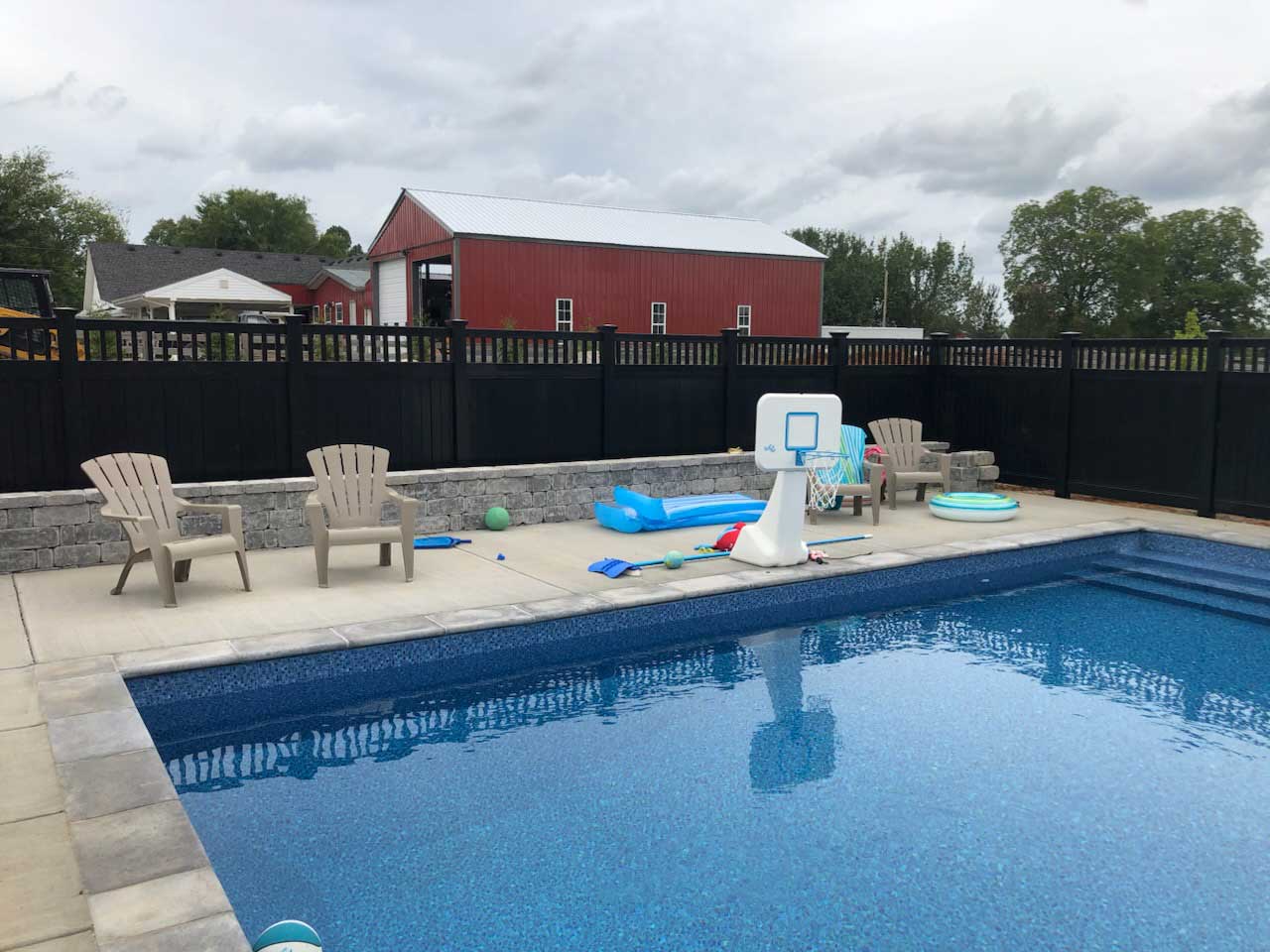 Picket top black vinyl privacy fence along residential pool