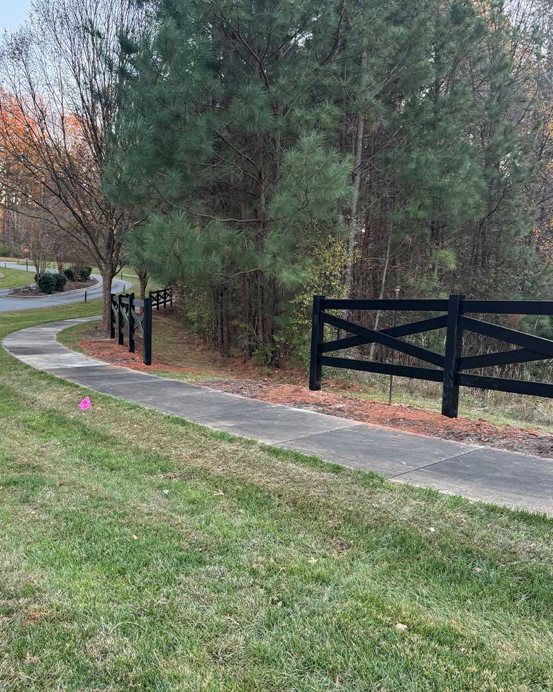 Crossbuck vinyl fence along sidewalk