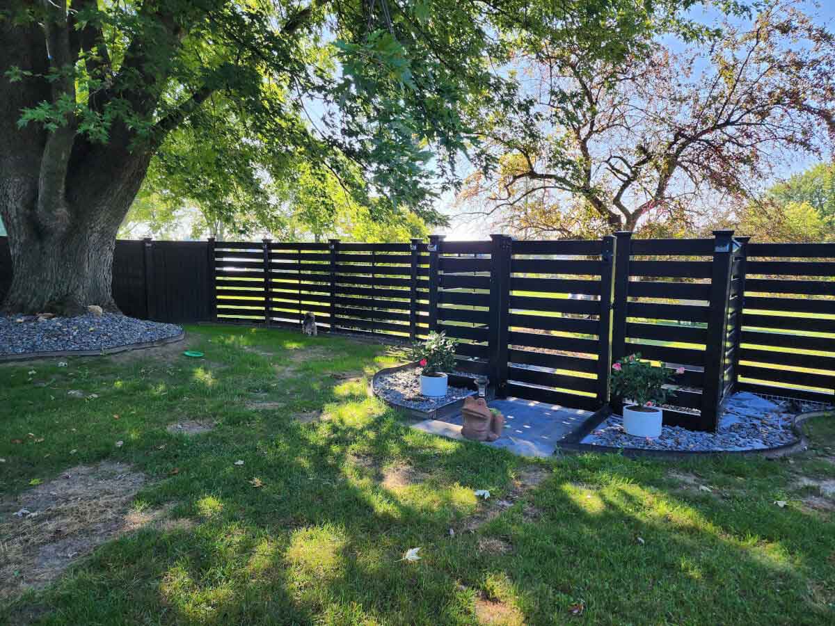 Horizontal semi-privacy black vinyl fence with gate entry and solar lighting.