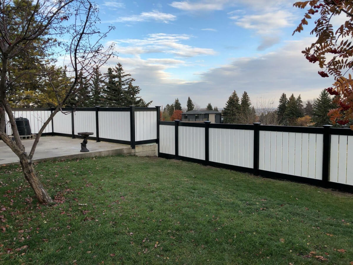 Residential vertical semi-private residential vinyl fence with black trim.