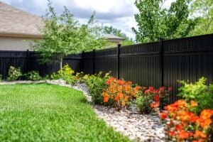 Backyard fence with landscaping, flowers, and home