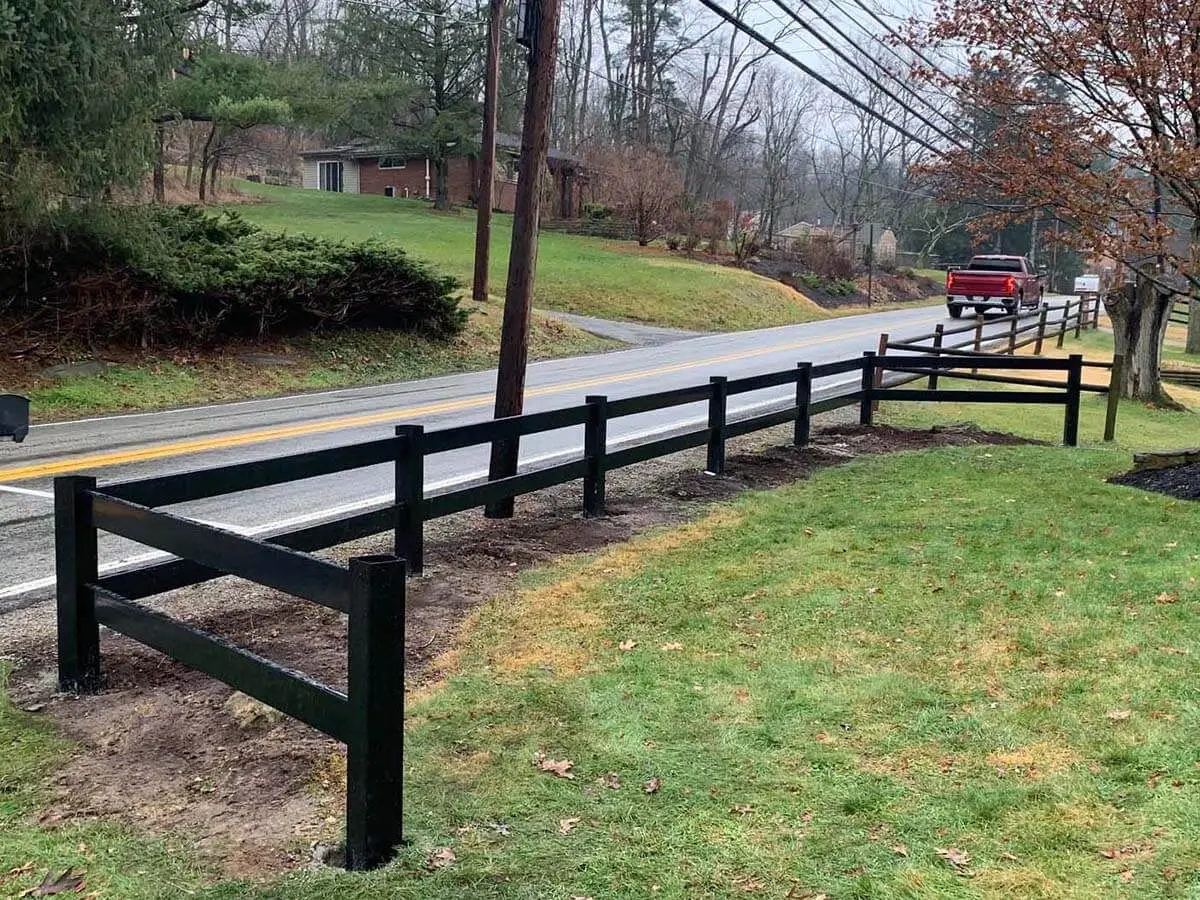 2 rail black vinyl fence installed around the front of a residential lawn