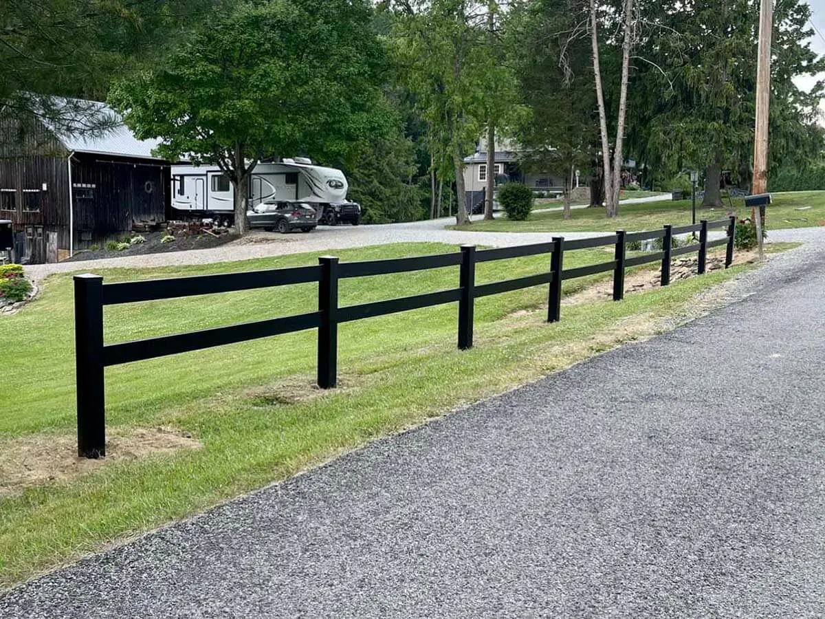 Black 2 rail vinyl ranch fence installed along a residential property line
