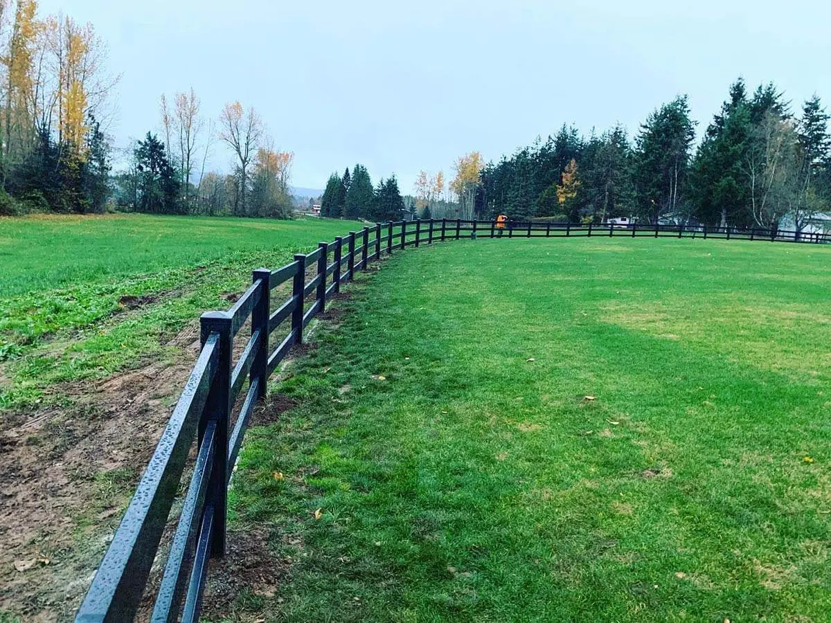 3 rail black vinyl ranch fence installed around a farm pasture