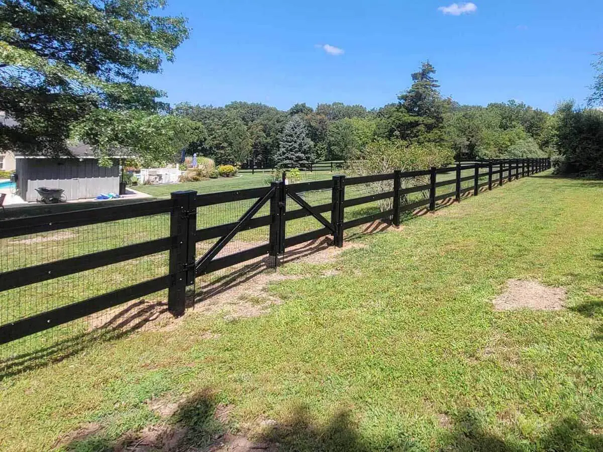 3 rail black vinyl farm fence with wire mesh and a double swing gate around a home