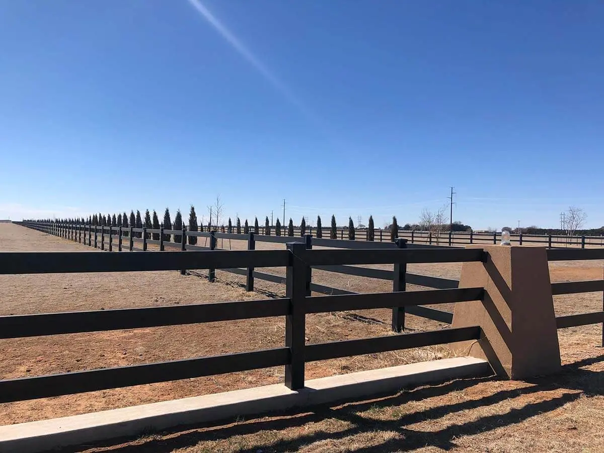 Black 3 rail vinyl fence installed around a pasture