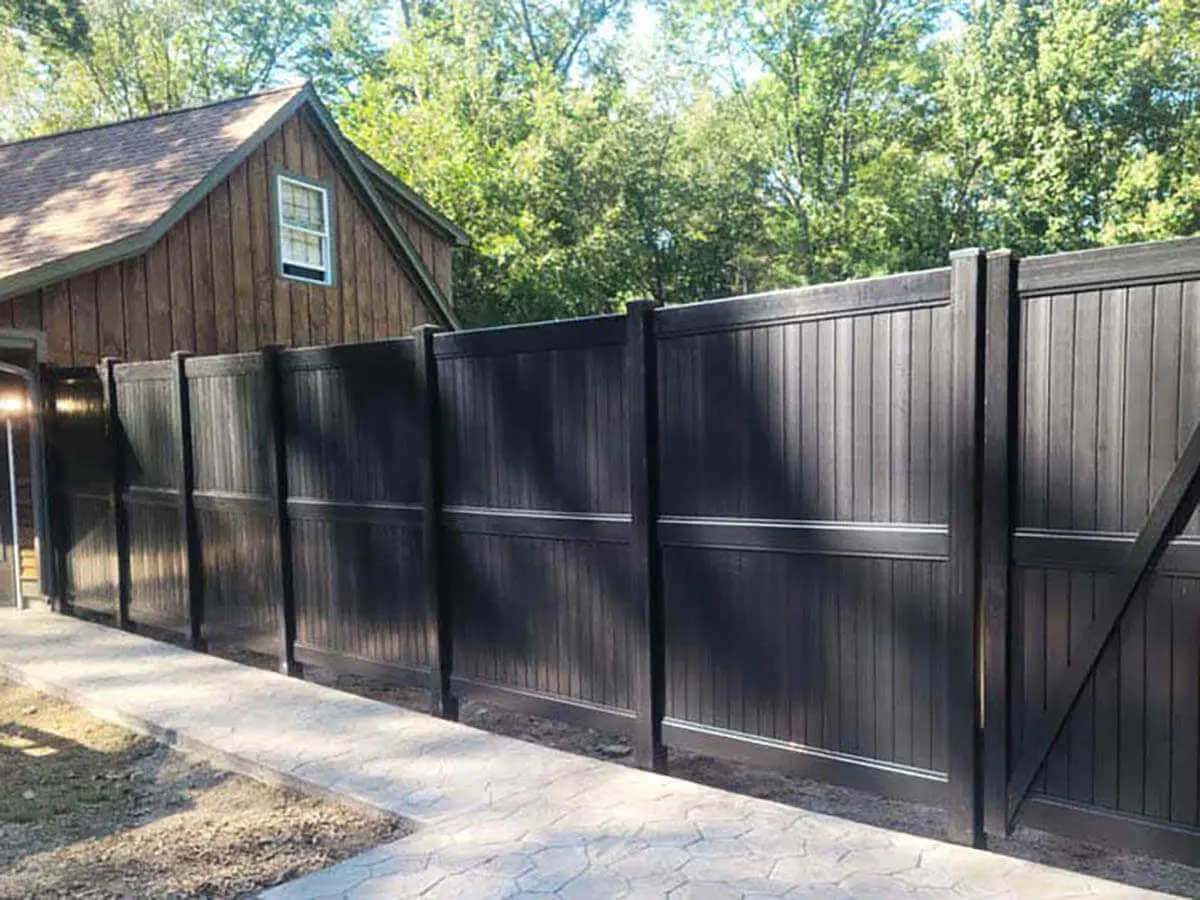 8 foot tall black vinyl privacy fence installed next to a barn