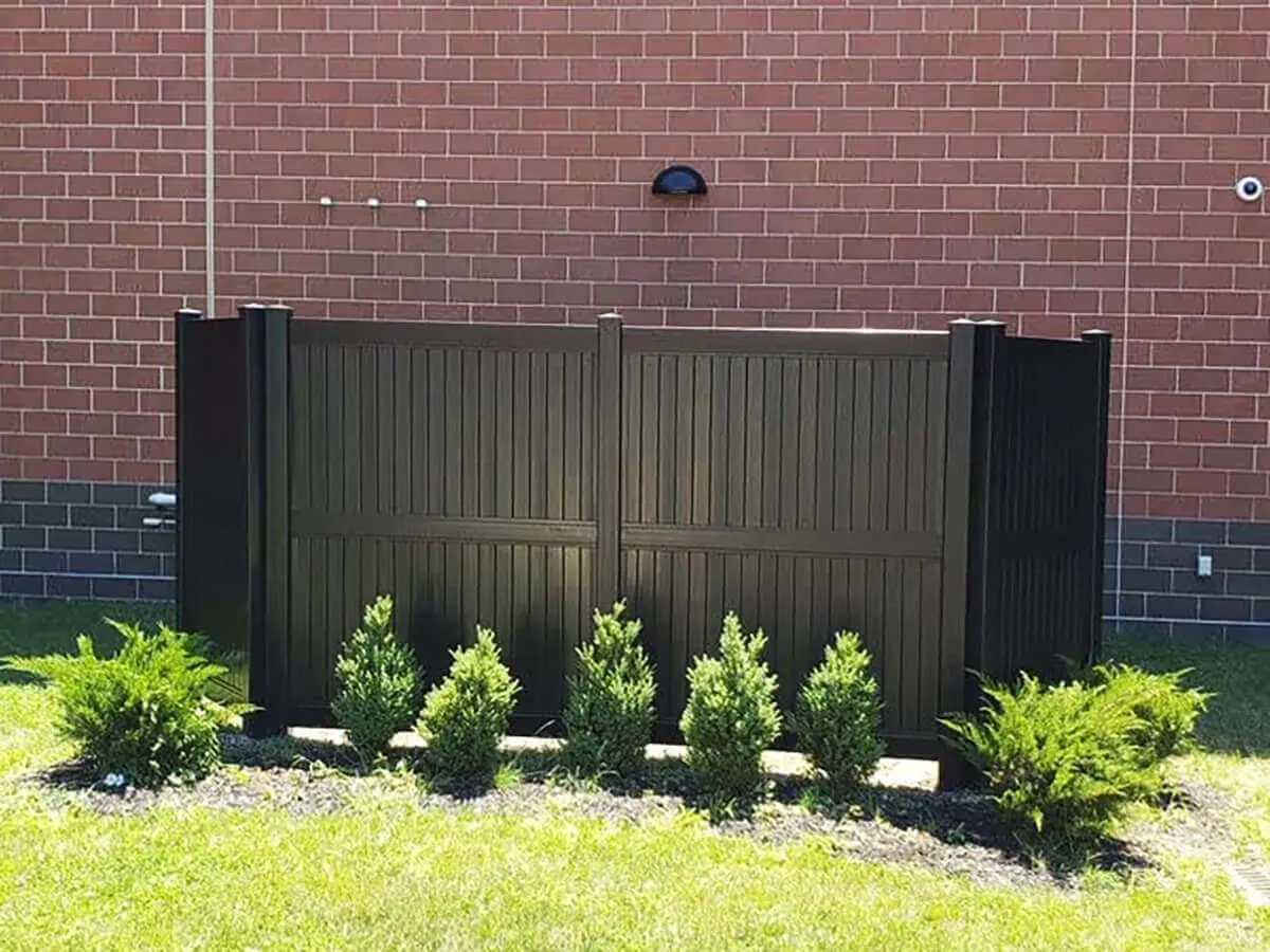 8 foot full privacy black vinyl fence enclosure installed along a brick building
