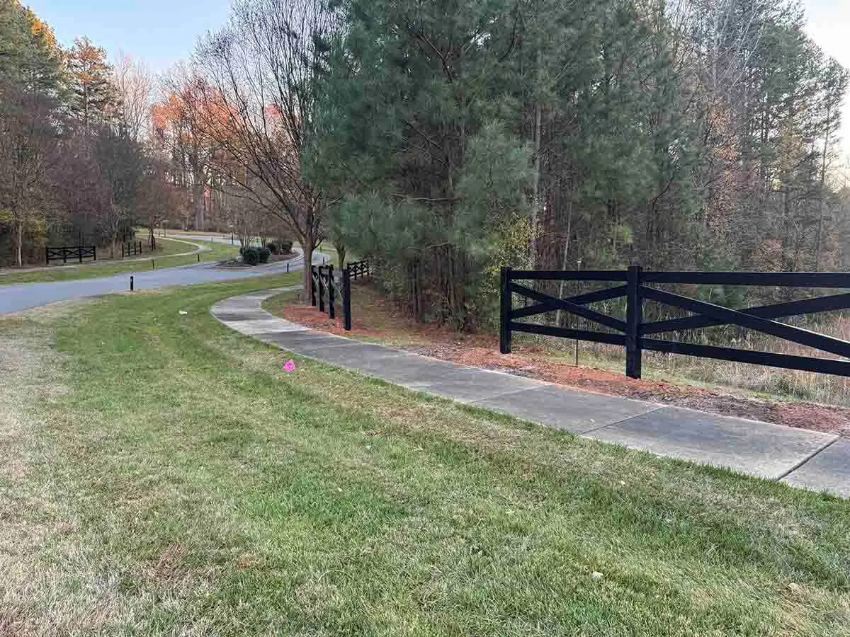 Black vinyl crossbuck ranch rail fence installed along a sidewalk