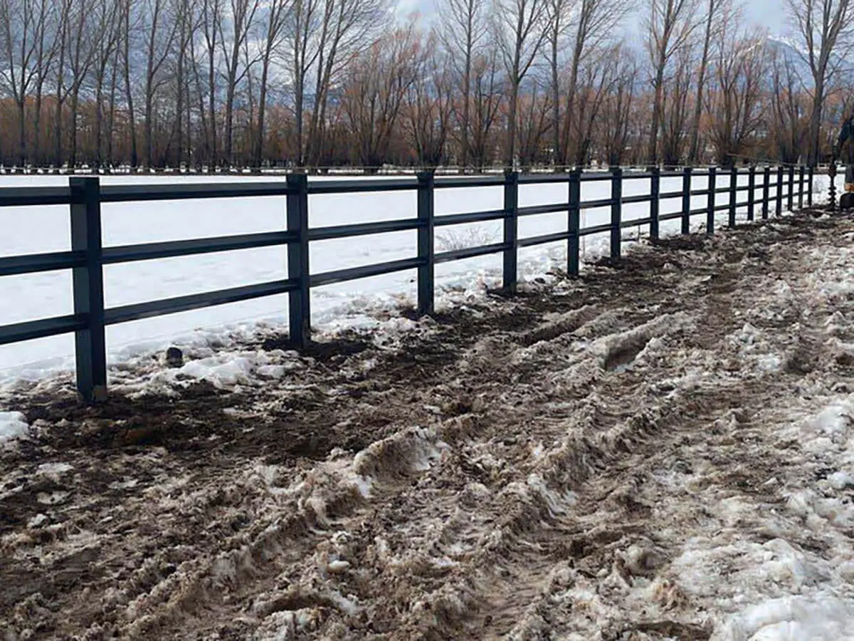 Black vinyl diamond rail horse fence installed on a snowy pasture