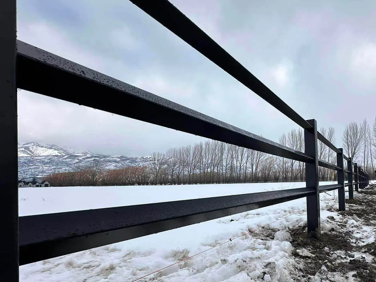 3 rail diamond rail farm fence installed around a farm property with snow