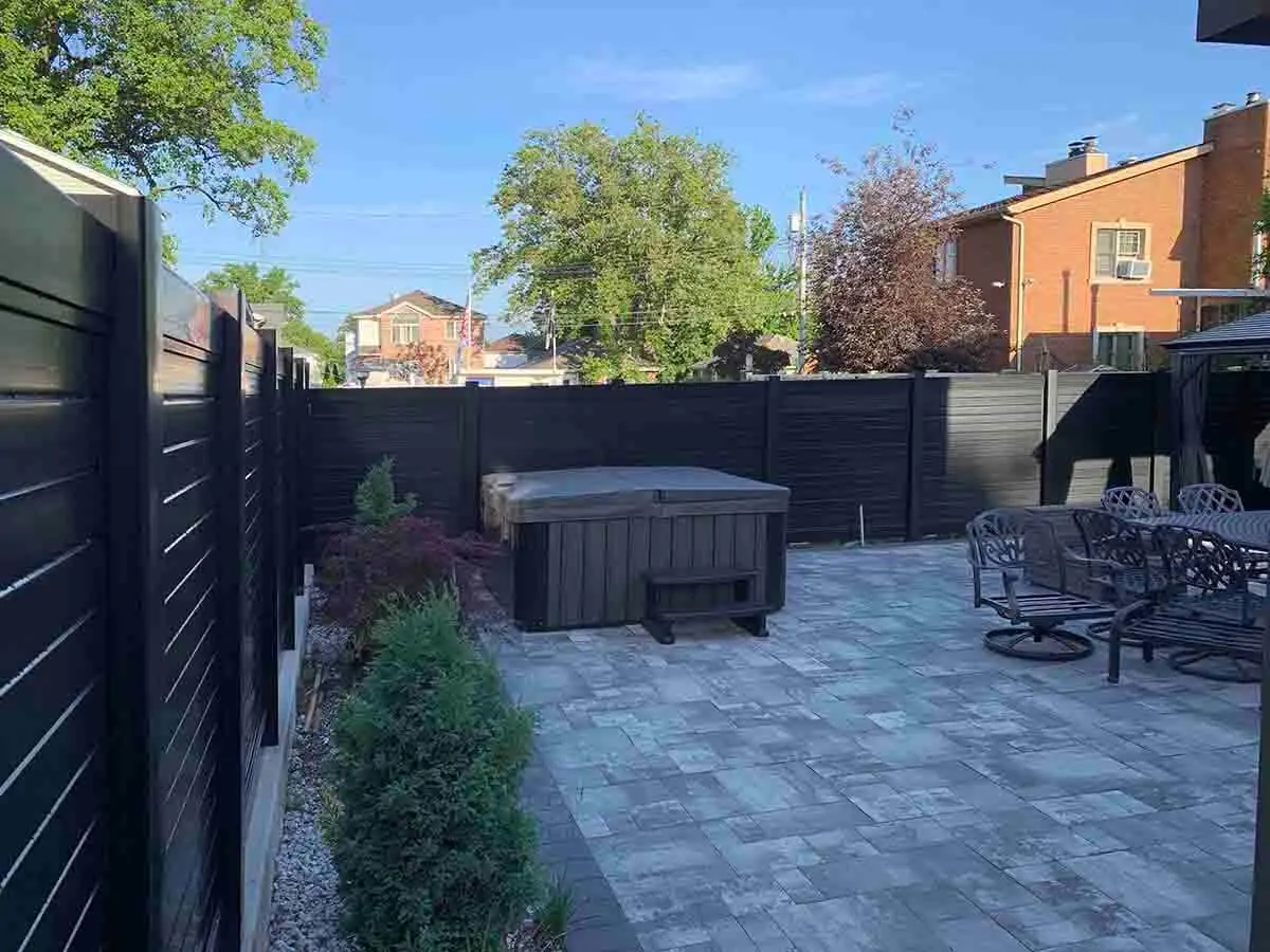 Black vinyl horizontal privacy fence installed around a residential backyard patio