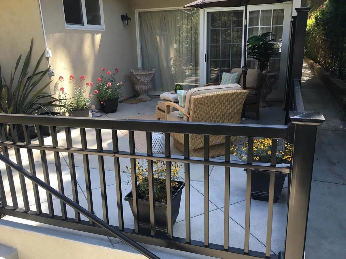 3 rail black vinyl railing installed around a residential home patio with a seating area