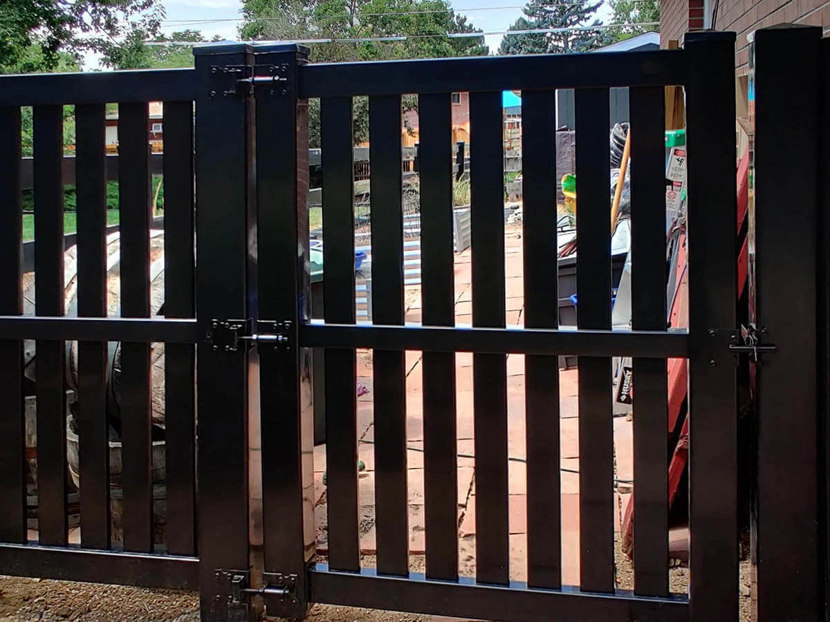 Semi-privacy black vinyl double swing gate with metal hinges on a residential property