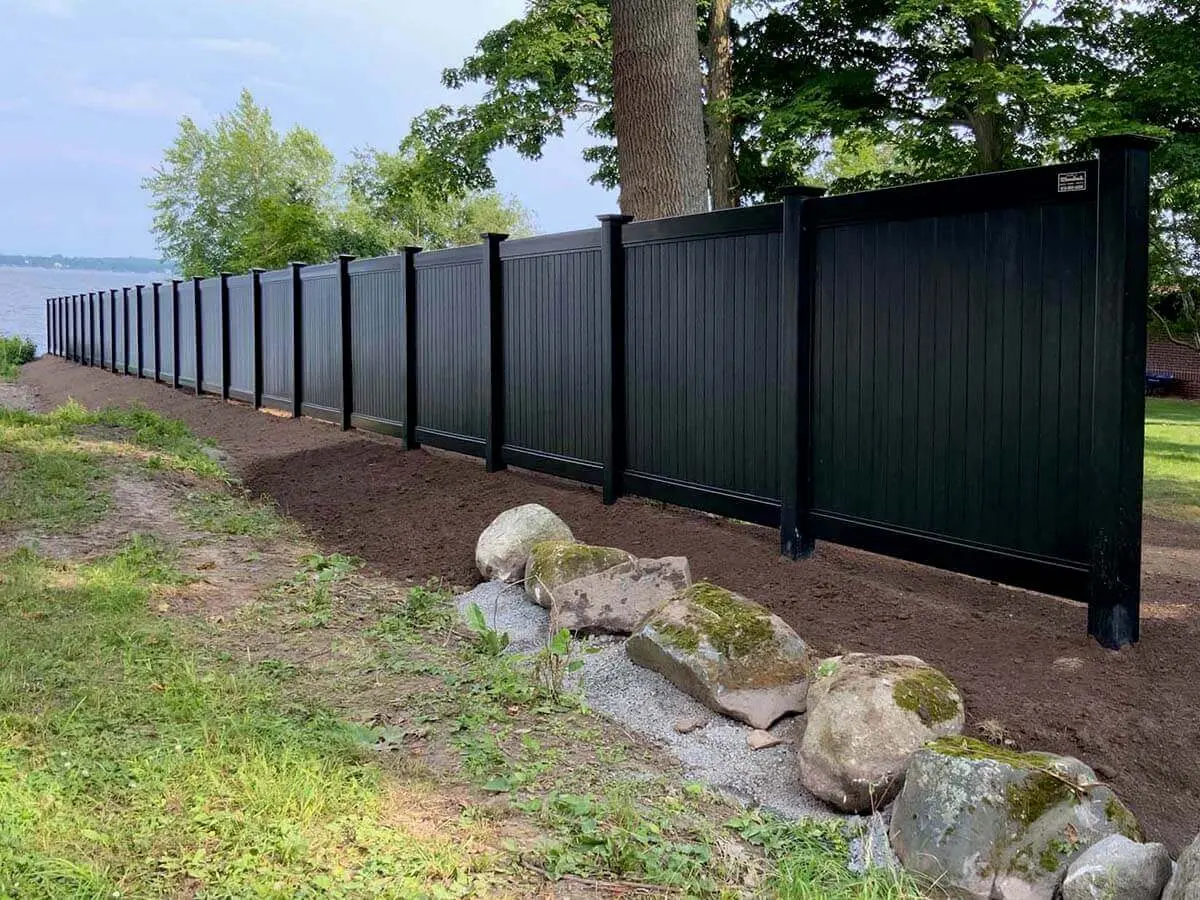 Full privacy black vinyl fence installed along a property line for a water front home