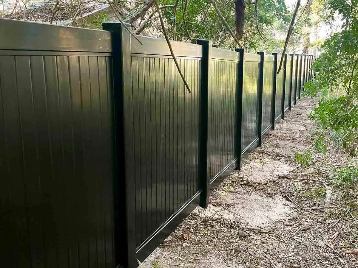 Black vinyl privacy fence installed along the edge of a property line