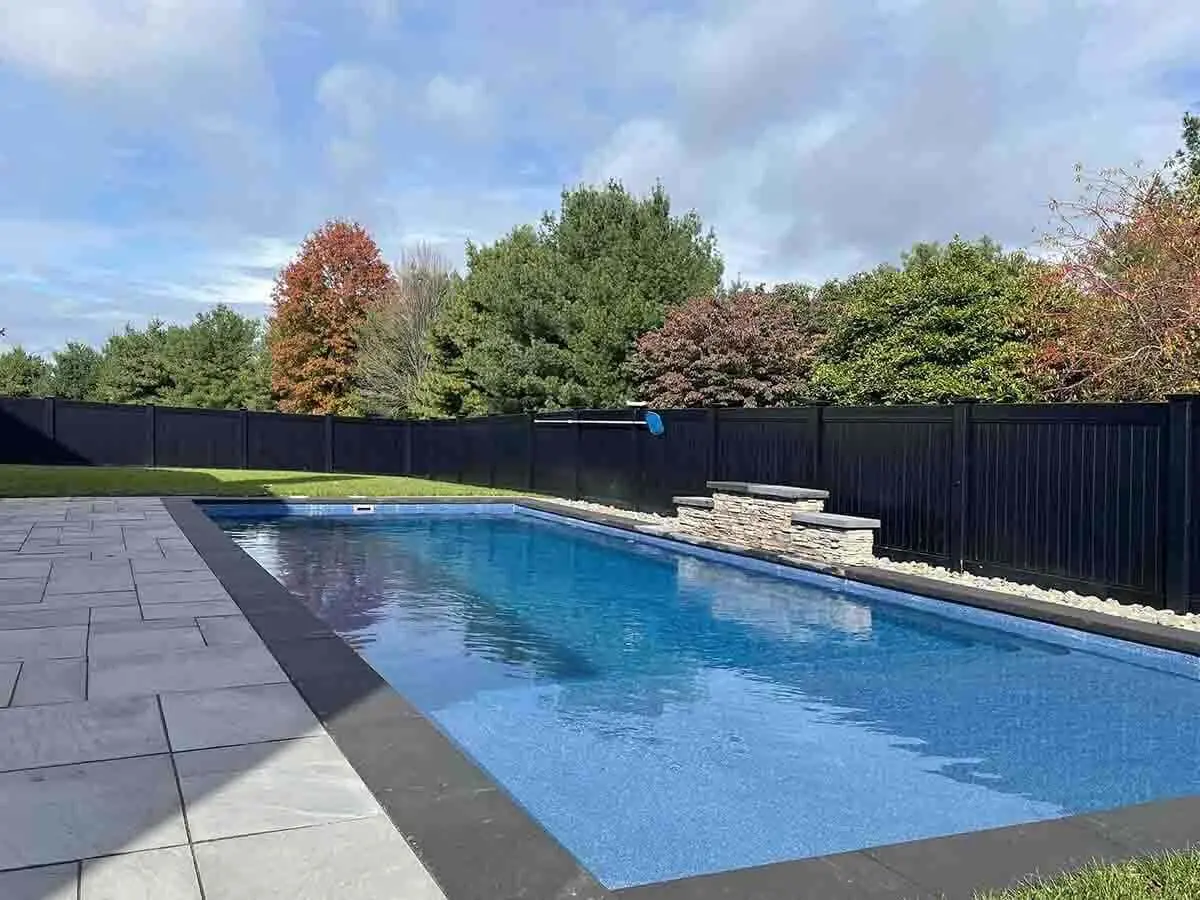 Black full privacy vinyl fence installed around a backyard with a pool and pavers