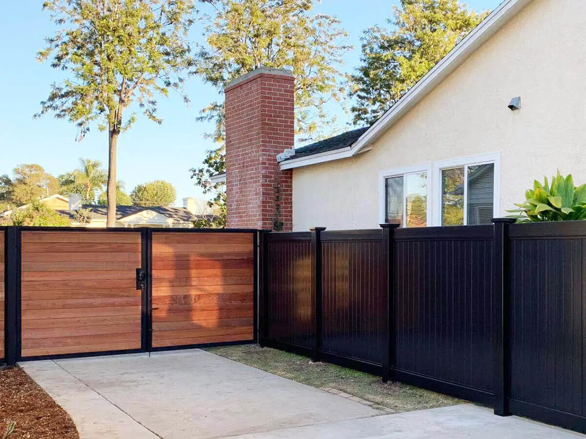 Black privacy vinyl fence installed next to a mixed material double swing gate