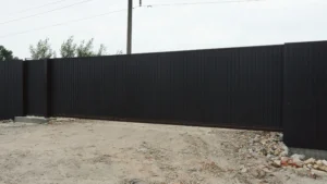 Black privacy fence panel with a sliding gate track